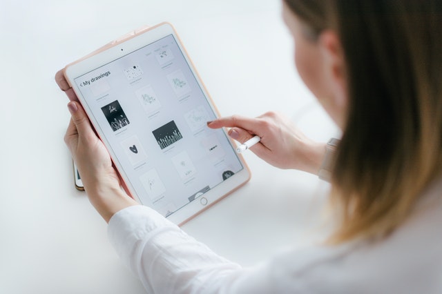 woman-sitting-beside-table-while-using-ipad-2265482